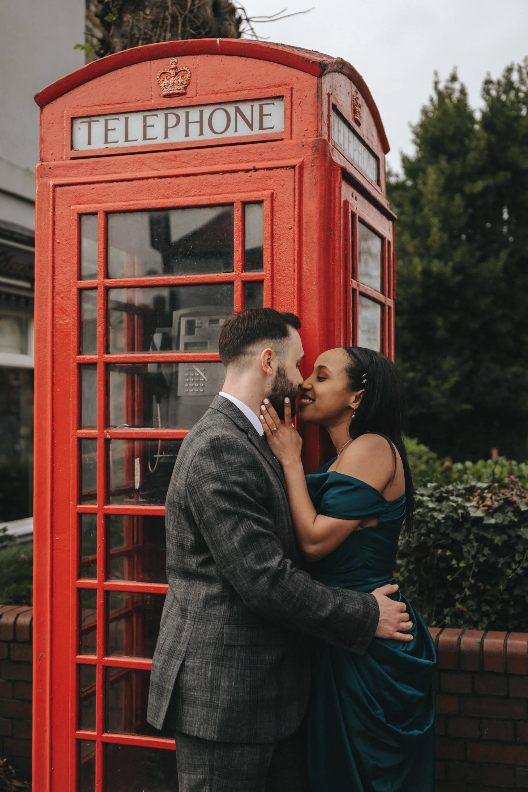 An engaged couple kissing in front of a red telephone booth, captured by a photographer in Yorkshire.