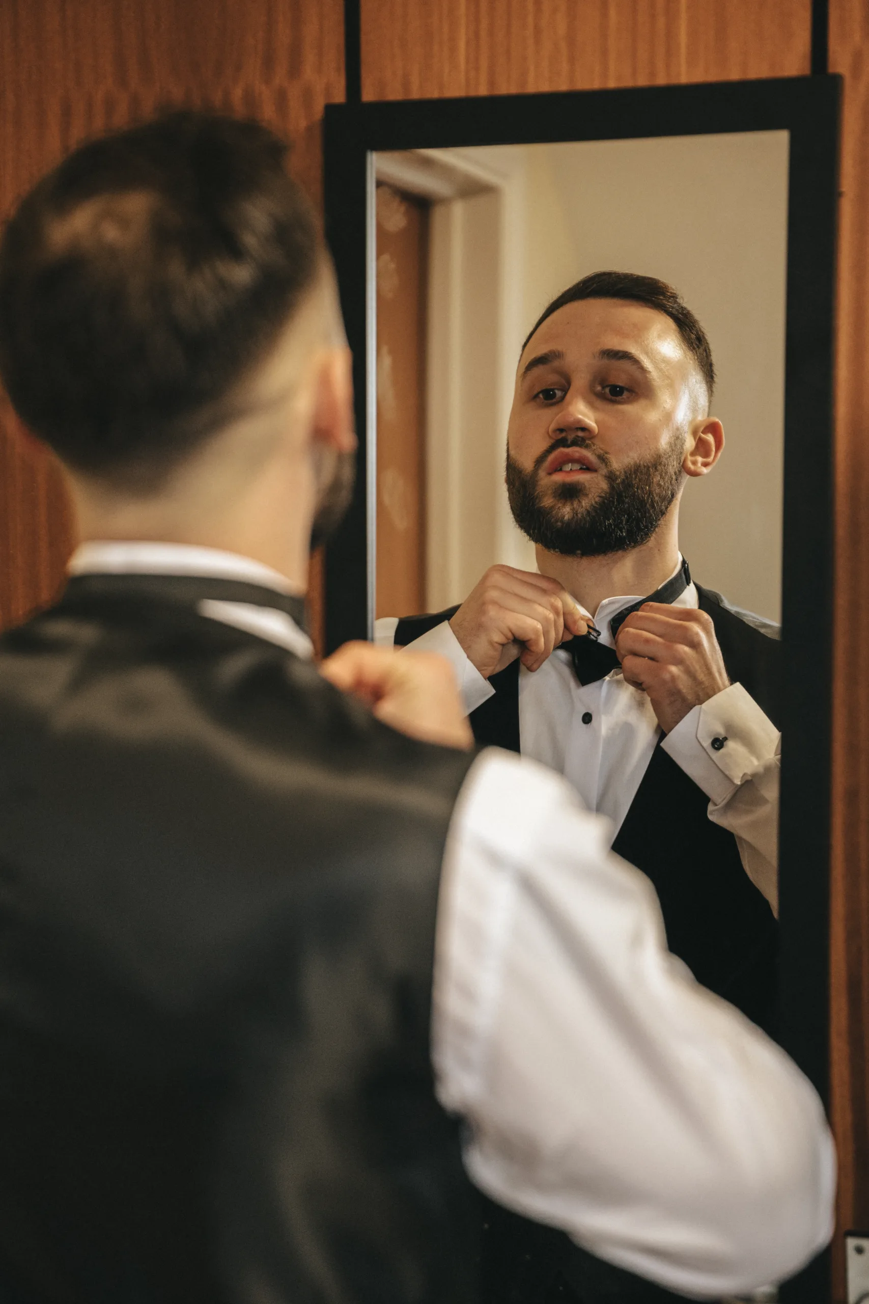 A man putting on a bow tie for a wedding in front of a mirror in Lincolnshire.