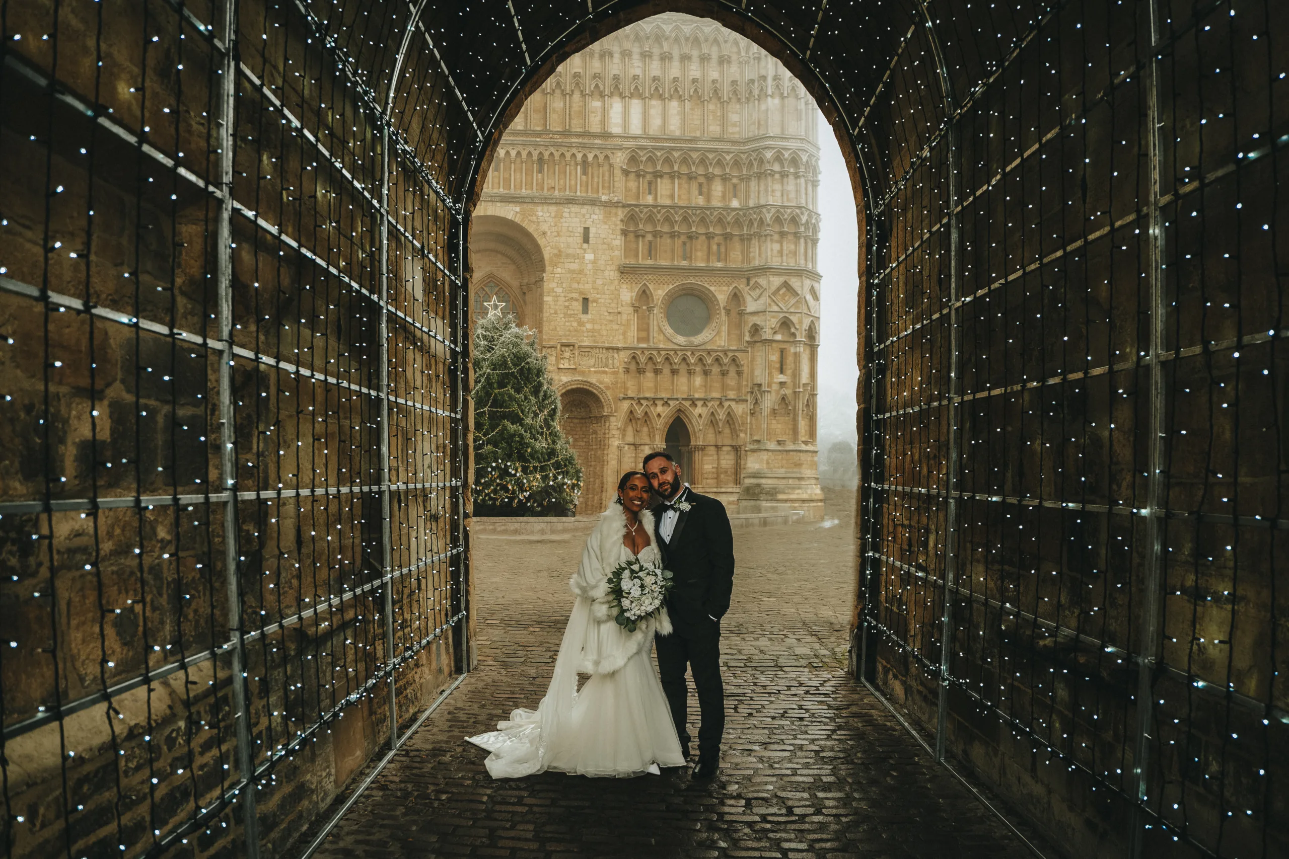 A bride and groom standing in an archway in front of a castle for their wedding.