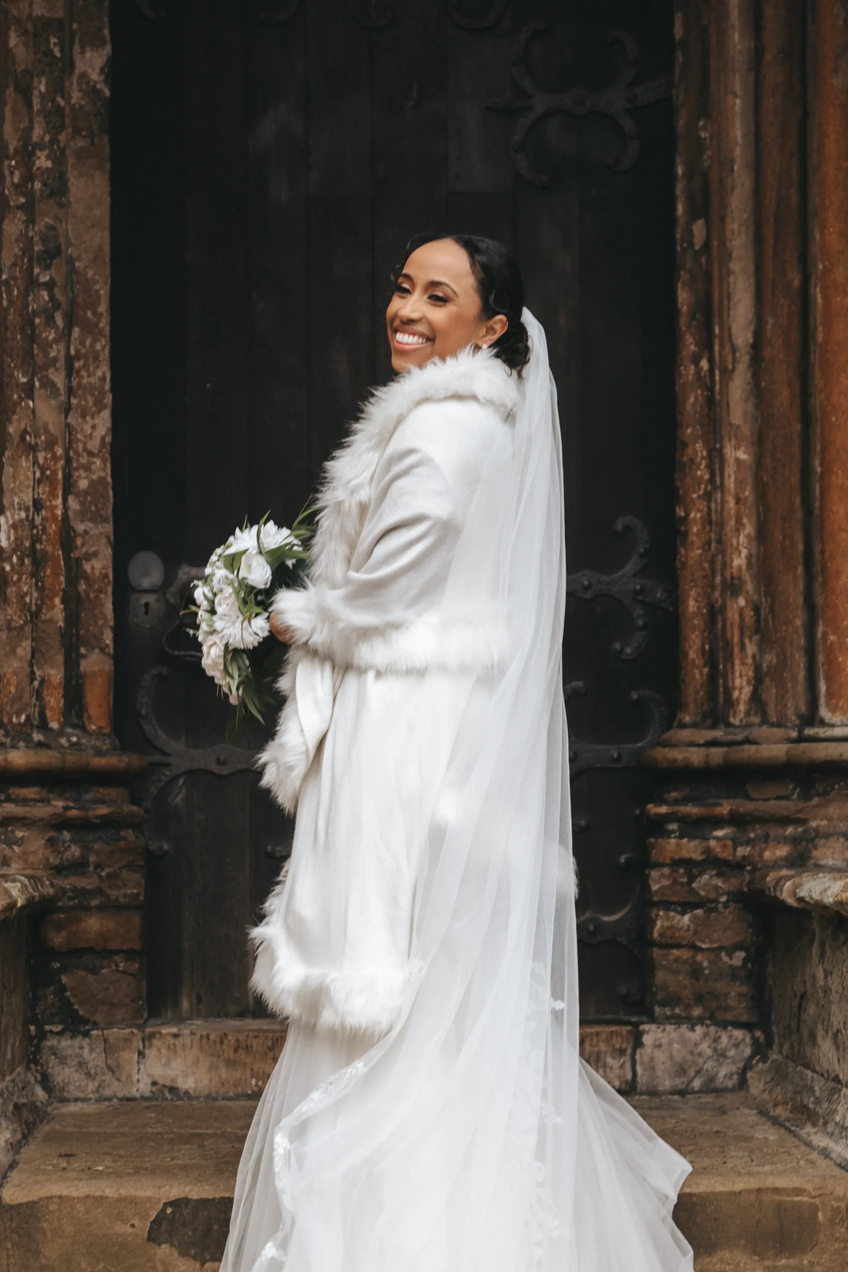 A bride in a white wedding dress standing in front of a door, captured by a Lincolnshire photographer.