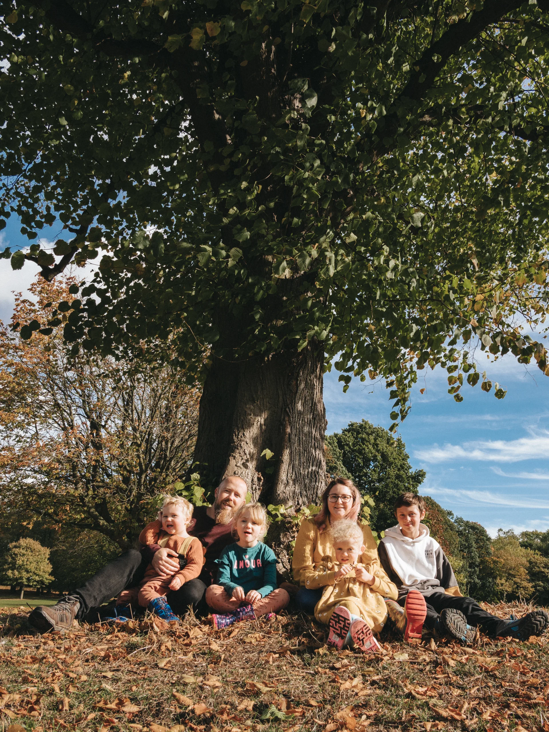 A family enjoys a picnic under a tree in a park.