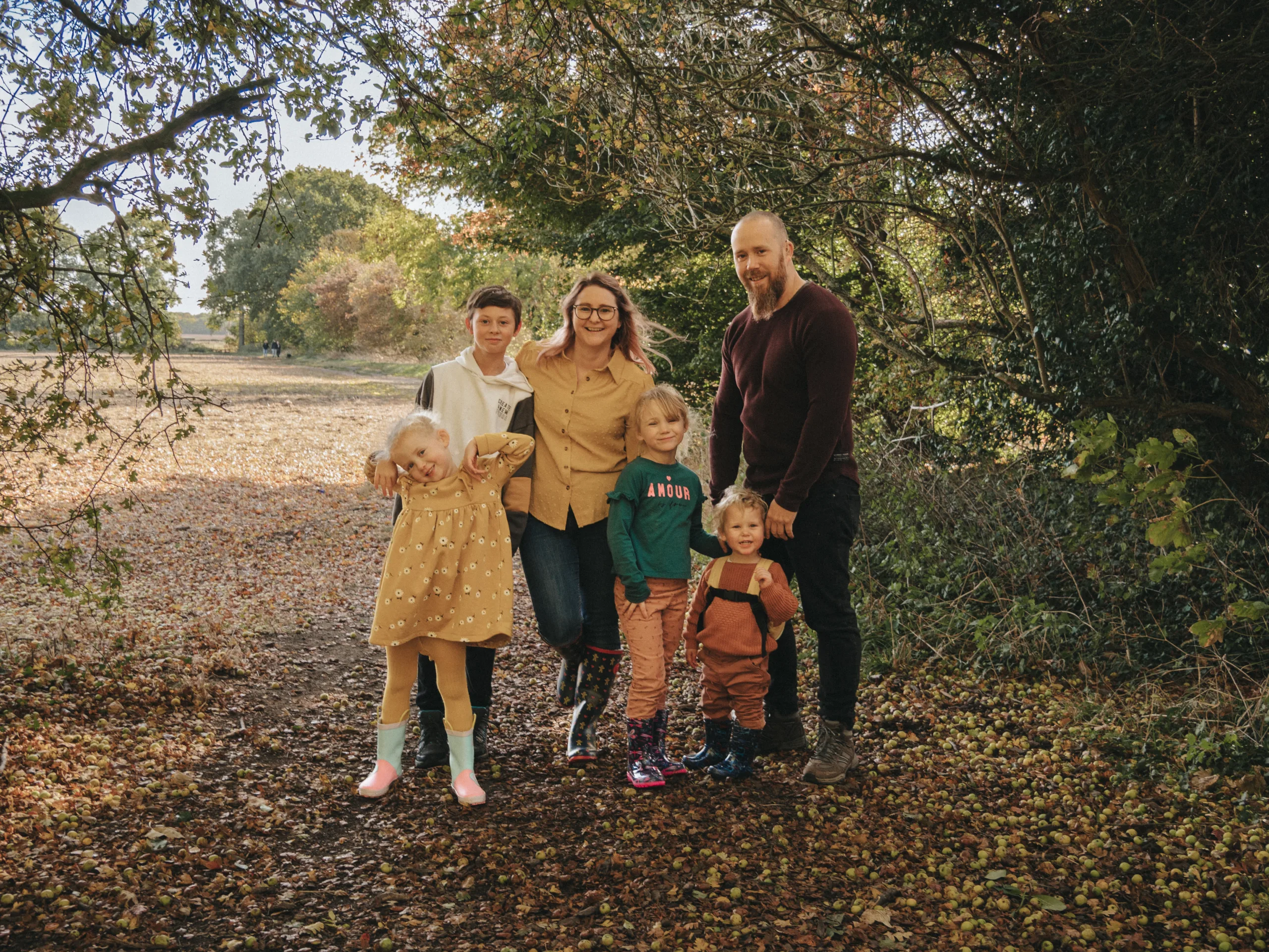 A family posing for a photo in a wooded area with a photographer.
