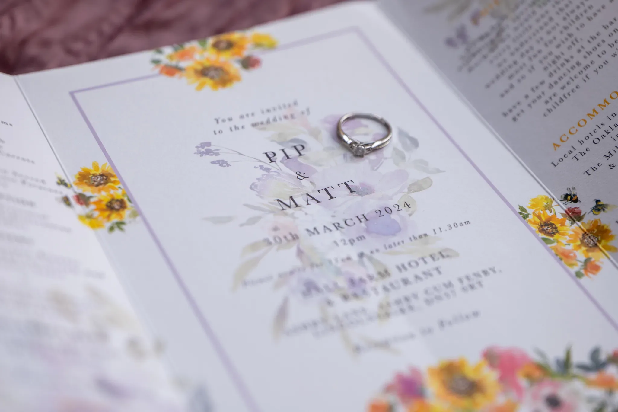 An elegant wedding invitation featuring floral designs with a pair of rings resting on the names "pip & mat," highlighting a special date in march 2024.