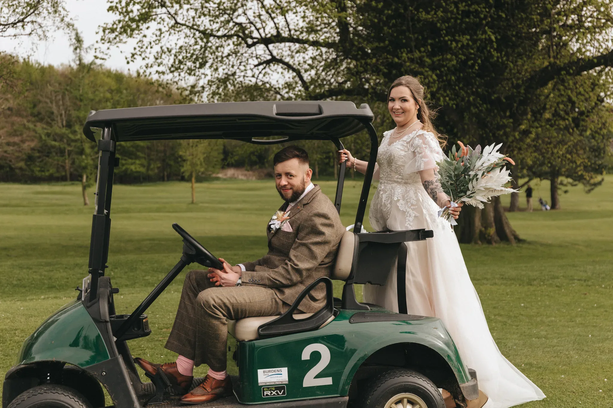 A bride and groom riding on a golf buggy at Grimsby Golf Club