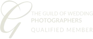 Logo featuring a stylized letter "G" with an elegant loop, followed by the text "The Guild of Wedding Photographers Qualified Member" in uppercase letters. The design is monochromatic, using a light gray color, and conveys a professional association related to wedding photography. © Aimee Lince Photography - Wedding photographer in Lincolnshire, Yorkshire & Nottinghamshire