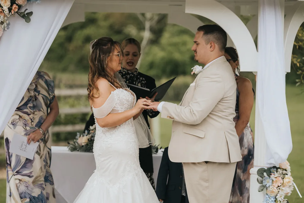 At Brackenborough, a bride and groom stand under a white gazebo, holding hands and gazing at each other during their wedding ceremony—a perfect moment captured by photography. © Aimee Lince Photography - Wedding photographer in Lincolnshire, Yorkshire & Nottinghamshire