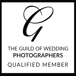 A black and white badge featuring a heart-shaped "G" at the top. Below, text reads: "THE GUILD OF WEDDING PHOTOGRAPHERS QUALIFIED MEMBER 2025," all on a white background with a black border—ideal for your Page Footer. © Aimee Lince Photography - Wedding photographer in Lincolnshire, Yorkshire & Nottinghamshire