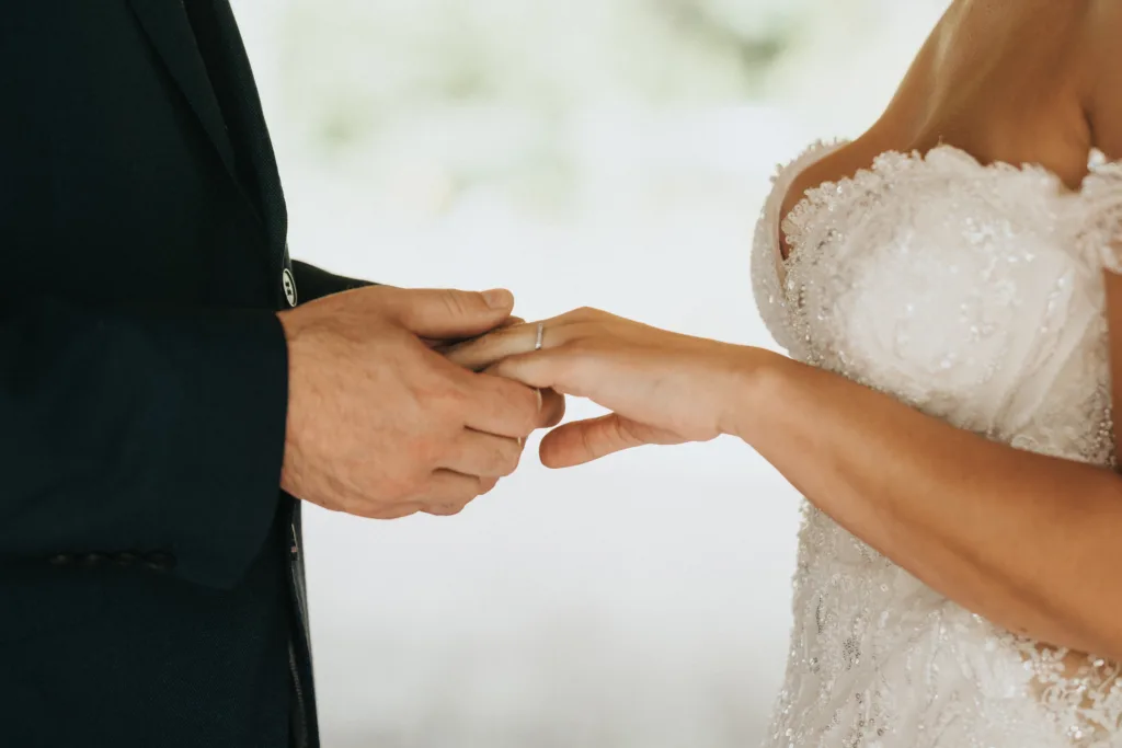 Close-up of a couple’s hands during a Hackness Grange wedding ceremony near Scarborough. The person on the left, in a dark suit, gently places a ring on their partner’s finger. Captured by a skilled wedding photographer with a softly blurred background. © Aimee Lince Photography - Wedding photographer in Lincolnshire, Yorkshire & Nottinghamshire