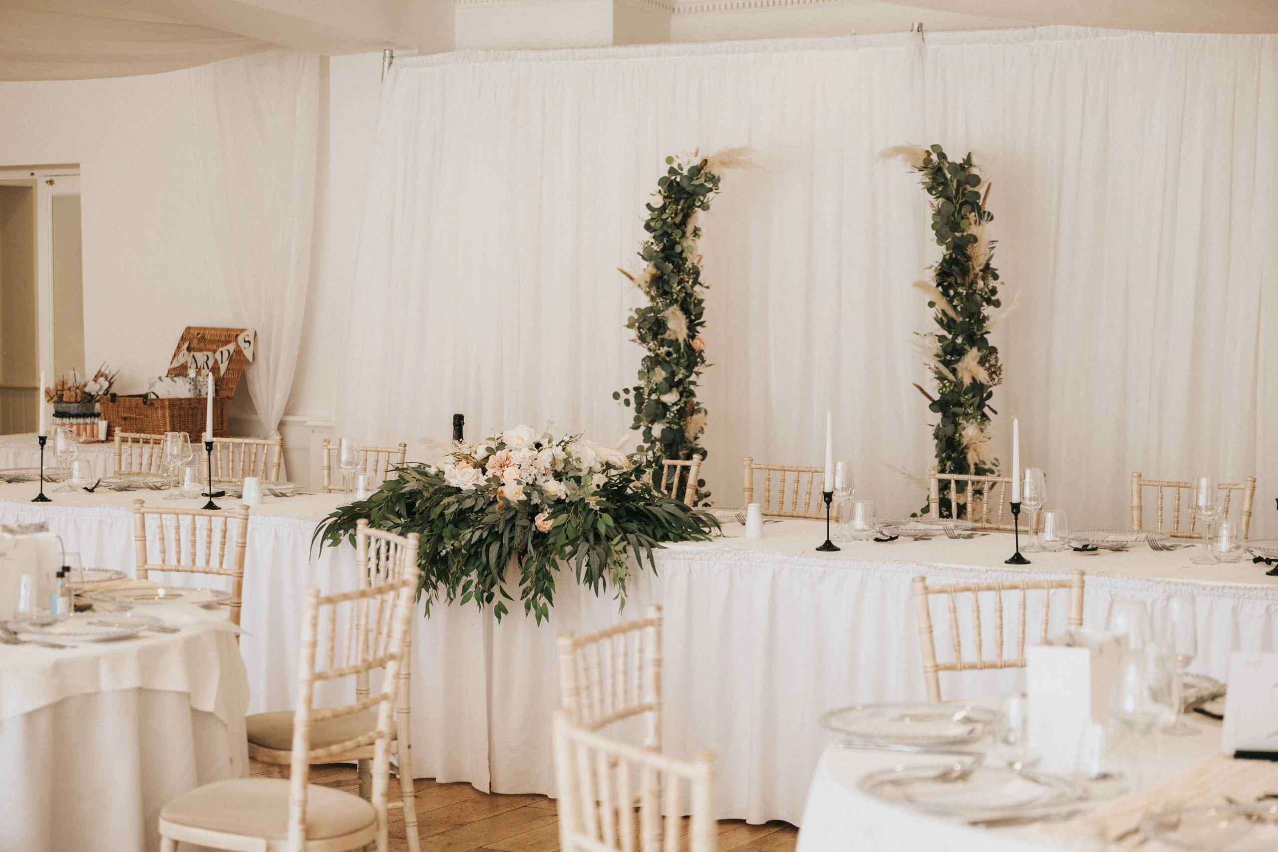 shane-carina-wedding-photography-scarborough-hackness-grange-photographer-copyright-aimee-lince-308-of-649-©-aimee-lince-photography-16-07-2025 Elegant wedding reception setup at Hackness Grange with long white tables, gold chairs, and clear plates. Two greenery arches and a central floral arrangement provide a stunning backdrop for any Scarborough wedding photographer to capture. © Aimee Lince Photography - Wedding photographer in Lincolnshire, Yorkshire & Nottinghamshire
