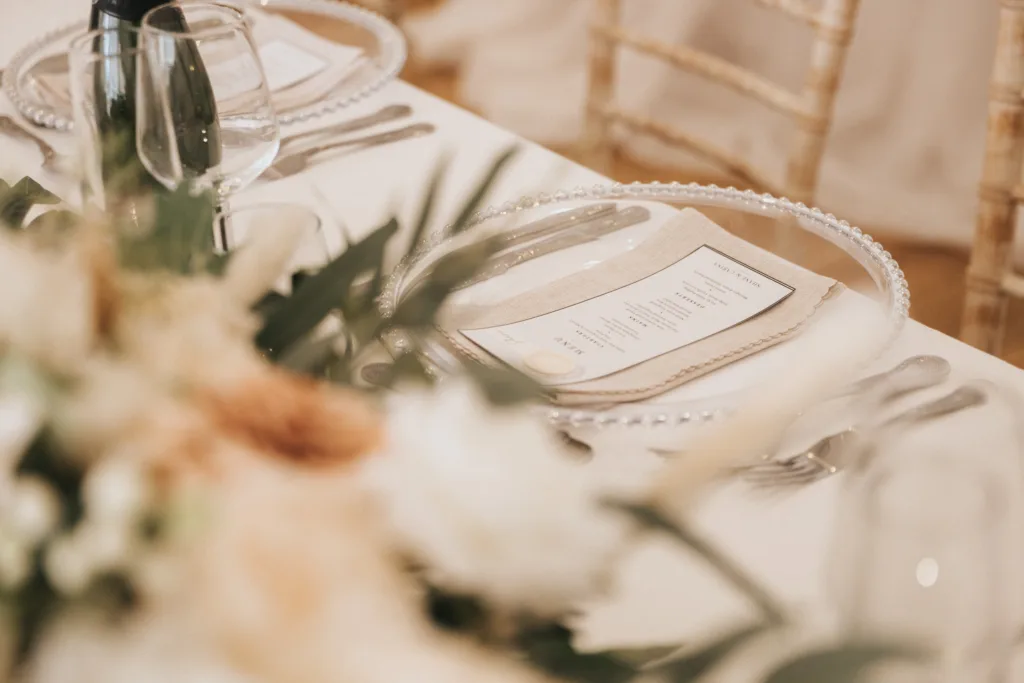 A close-up of an elegant table setting at Hackness Grange in Scarborough, featuring a beaded glass plate with a printed menu, silver cutlery, and soft florals—perfect inspiration for a wedding photographer capturing formal event details. © Aimee Lince Photography - Wedding photographer in Lincolnshire, Yorkshire & Nottinghamshire